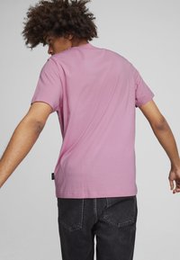 Lila Baumwoll-T-Shirt mit kurzen Ärmeln und rundem Ausschnitt. Zeigt ein schlichtes Design mit einem kleinen Logo-Tag am Saum.