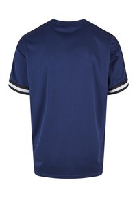 Námořnická modrá sportovní košile s mřížkovou texturou. Obsahuje černobílé pruhované akcenty na rukávech. Pohled zezadu, krátké rukávy.