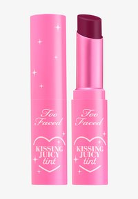 Roze lippenstift tube met een glanzende afwerking, versierd met decoratieve sterren. De dop onthult een diep bessenkleurige getinte lippenbalsem. Tekst: "Too Faced Kissing Juicy Tint."