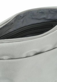 Borsa in tessuto argento con apertura con zip, che rivela un interno grigio liscio e una tasca orizzontale con zip.