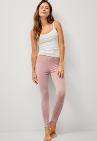 Fluwelen roze leggings met een slim fit, gecombineerd met een witte tanktop met gekartelde randen. Geen zichtbare patronen of hardware.