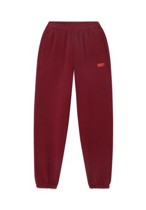 Burgundy sweatpants with an elastic waistband, side pockets, and tapered legs. Notable logo printed in pink on the left side.