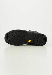 Schwarze Outdoor-Schuhsohle mit strukturiertem Muster, tiefen Profilen und einem markanten gelben Akzent. Hergestellt aus strapazierfähigem Gummimaterial.