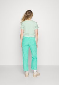 Mentolové tričko s krátkým rukávem v kombinaci se světle mentolovými manšestrovými kalhotami. Tento outfit má volný střih a jemný, texturovaný povrch.