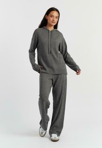 Sweat à capuche gris avec une coupe décontractée, des poignets côtelés et un pantalon large gris assorti. Texture douce, détails de couture minimalistes, design simple.