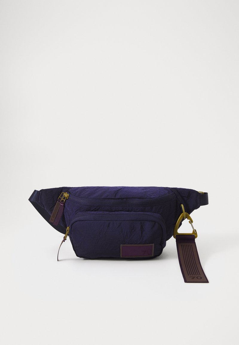 Violets krunkāta auduma hipster soma ar divām rāvējslēdzēju kabatām, zelta aksesuāriem un noņemamu siksniņu ar tekstūras akcentu.