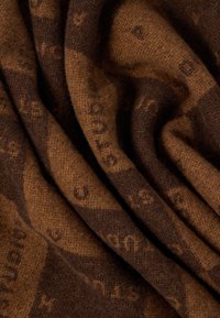 Tessuto marrone intrecciato con un motivo sottile. Superficie texturizzata con sfumature di marrone variabili, che creano un aspetto ricco e stratificato.