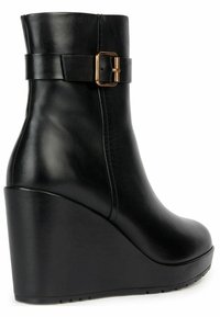 Stivale ankle nero con tacco a cuneo realizzato in pelle liscia, caratterizzato da un dettaglio con fibbia laterale e punta arrotondata. Superficie texturizzata con design del tacco arrotondato.