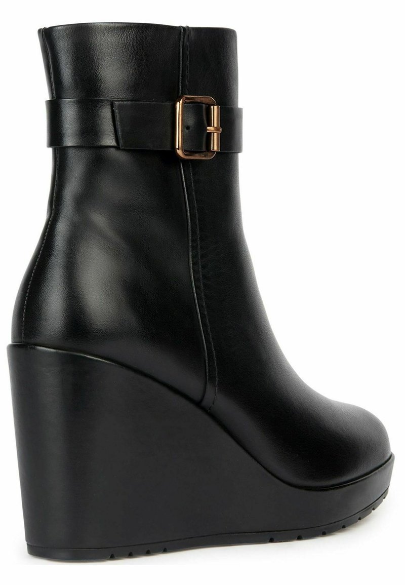 Bota de tobillo negra de cuña, hecha de piel lisa, con un acento de hebilla lateral y punta redondeada. Superficie texturizada con un diseño de tacón redondeado.