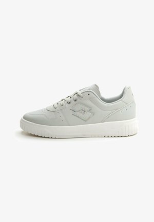 Zapatillas deportivas de color gris claro con un acabado de cuero suave, puntera perforada y suela de goma blanca. Presenta un logo sutil en el lado.