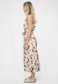 Maximekko kuvioidusta kankaasta, jossa on beigejä, oransseja ja mustia sävyjä. Ohuet hihnat, istuva vyötärö nauhalla, laskeutuva helma ja hienovarainen kiilto.