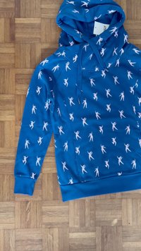 Hoodie azul feito de tecido macio, apresentando um padrão de silhuetas humanas brancas, com um bolso frontal e cordão ajustável.