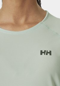 Camiseta atlética de manga corta de color verde claro con cuello redondo y tejido texturizado de canalé. Logo negro impreso en la zona del pecho izquierdo.