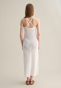 Abito maxi in maglia bianco, con spalline incrociate e un motivo a chevron su un tessuto traspirante e testurizzato, con orlo dritto.