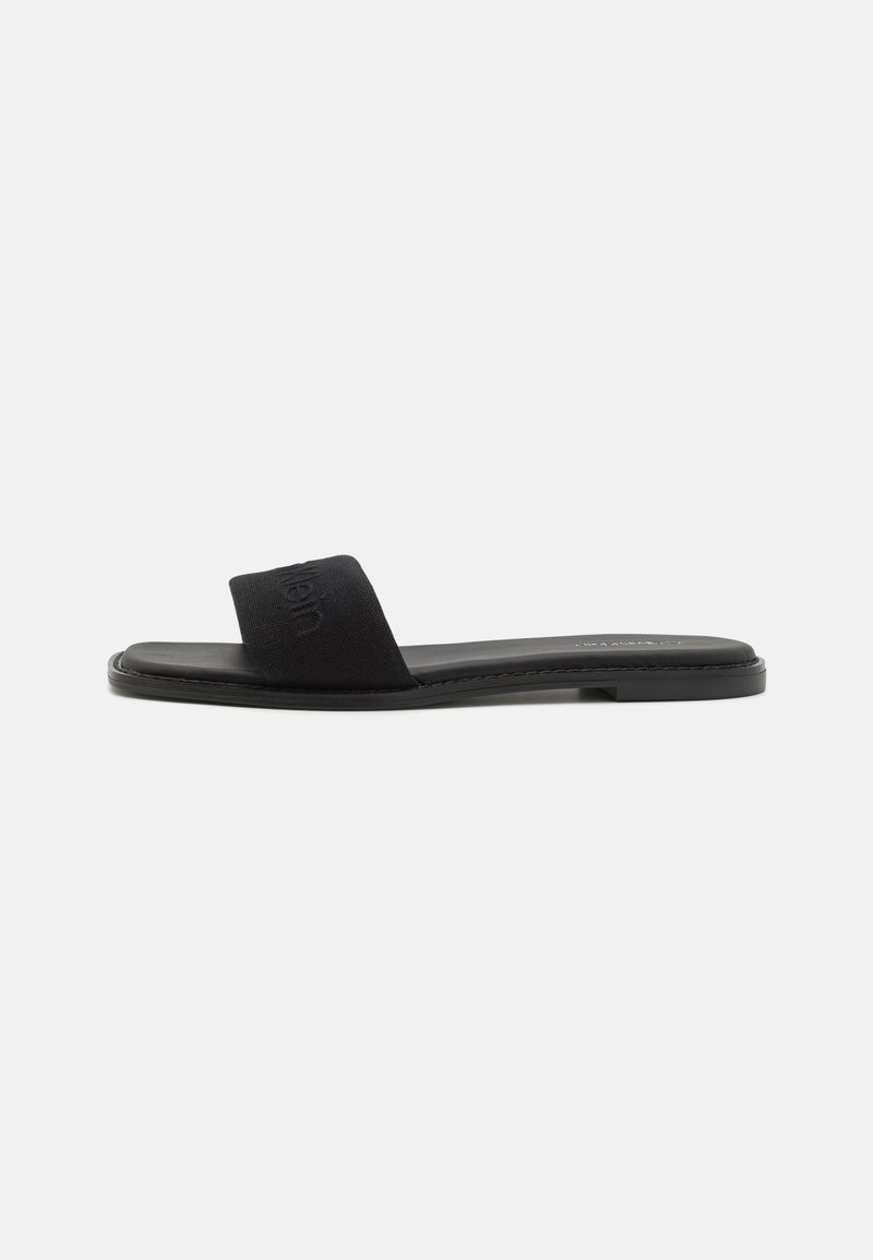 Black slide sandal with a fabric strap and flat sole. Features a subtle embossed logo on the strap and minimalistic design. Smooth texture.