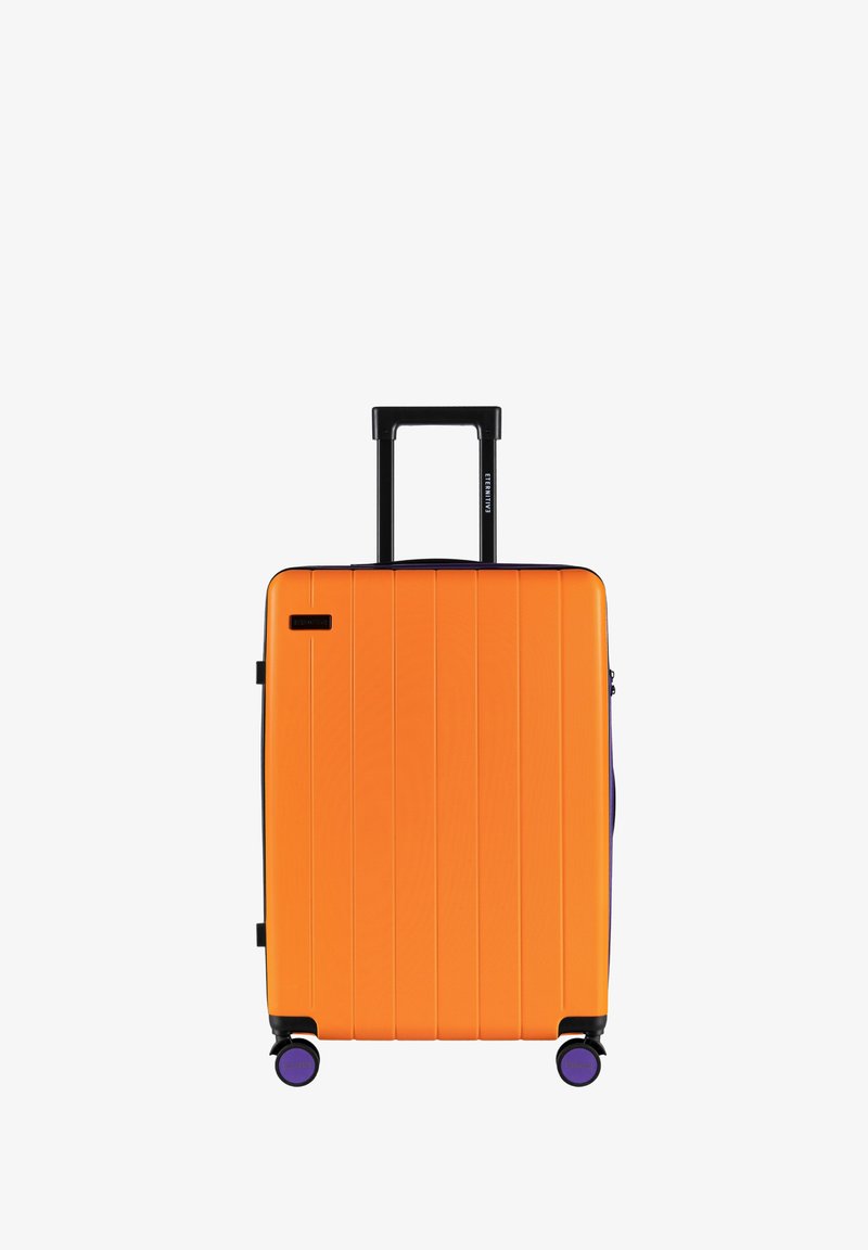 Twarda walizka w jaskrawym pomarańczowym kolorze z pionowymi rowkami, czarną wysuwaną rączką i fioletowymi kółkami. Posiada zamknięcie na zamek oraz boczną kieszeń.