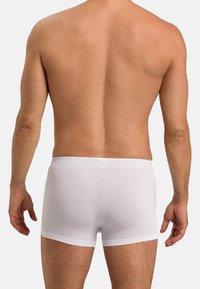 Bílé bavlněné boxerky s těsným střihem, které mají měkký pás a žádné viditelné vzory. Látka vypadá hladce a je lehká.