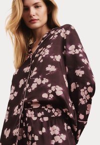 Seiden-Schlafanzugset in dunklem Burgunder mit hellrosa Blüten. Besteht aus einem Hemd mit Kragen und einem elastischen Bund, samtiger Textur.