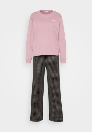 Jasnoróżowa bluzka z długim rękawem z detalami logo, sparowana z czarnymi spodniami o szerokich nogawkach z wzorem diamentów. Oba elementy mają miękką fakturę.
