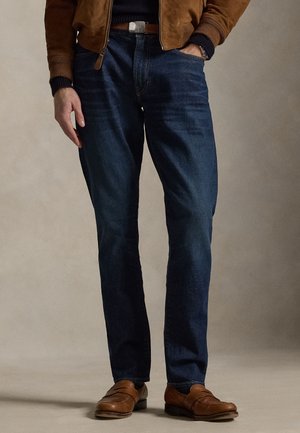 Dunkelblaue Jeans mit geradem Bein, einem dezenten Waschungseffekt, positionierten Taschen und einem klassischen Knopfverschluss.