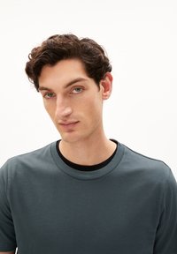 Korte mouwen, ronde hals t-shirt in donkerblauwe stof. Heeft een gladde textuur en een contrasterende zwarte binnenkraag.