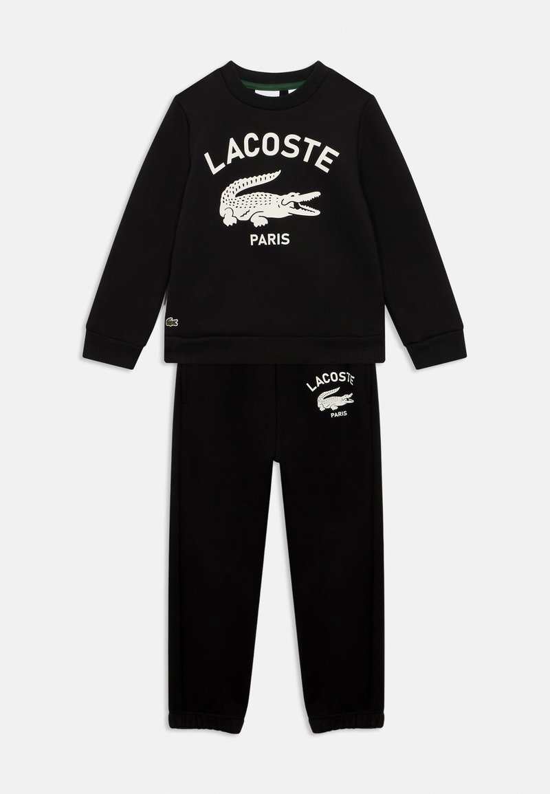 Schwarz Sweatshirt- und Hosen-Set mit weißem Lacoste-Logo und Krokodil-Grafik auf der Brust und dem linken Oberschenkel, entworfen für Freizeitmode.
