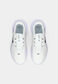 Άσπρα αθλητικά παπούτσια με πλέγμα υφάσματος, στρογγυλή μύτη, γκρι λεπτομέρειες, μαύρο λογότυπο Nike και λευκά κορδόνια σε ανοιχτή σόλα.
