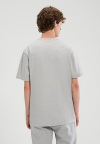 Grijze katoenen T-shirt met korte mouwen en een ronde hals, met een gladde textuur en een losse pasvorm. Achteraanzicht toont een eenvoudig ontwerp.