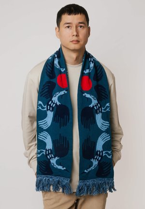 Tkany szal w kolorze morskim z wzorem ptaków w odcieniach niebieskiego z czerwonymi akcentami. Brzegi ozdobione frędzlami dodają tekstury i detali.