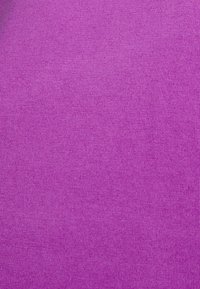 Närbild av lila stickad tyg som visar fint, jämnt stygn och slät textur.