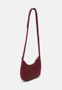 Borsa a spalla in pelle bordeaux con forma curvata. Presenta una cerniera dorata e una lunga tracolla regolabile con più fori per la dimensione.