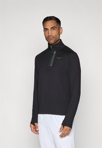 Tricou negru cu mânecă lungă, tip fermoar, având un guler înalt și un fermoar parțial. Material neted cu un logo subtil în gri închis.