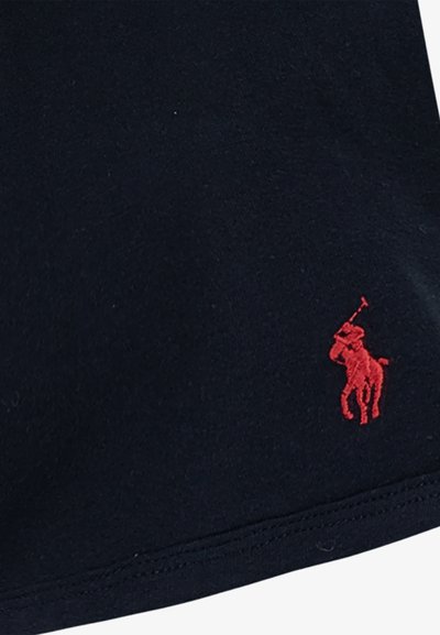 Mornarsko modra bombažna tkanina z gladko teksturo ima majhen rdeč izvezeni logo polo igralca na spodnjem levem delu.