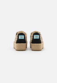 Leopard print espadrilles with black suede accents and braided jute soles, featuring a light blue TOMS logo on the heel.