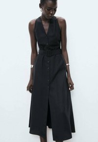 Black sleeveless dress with a fitted bodice, a belt at the waist, and button-down front. Material appears smooth with a slight sheen.