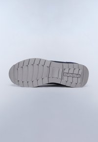 Semelle de chaussure en caoutchouc gris texturé, présentant un motif de semelle et un marquage. La vue inférieure montre une zone lisse et plate avec des rainures bien définies.