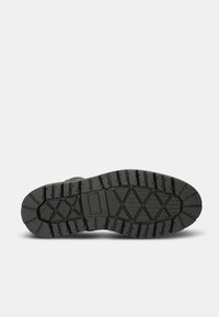 Suela de bota de goma negra con un patrón de banda de rodadura profundo, superficies texturizadas y bordes reforzados para mejorar el agarre y la durabilidad.