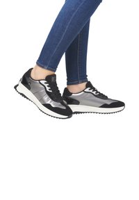 Des baskets noires et argentées au design élégant, avec une finition brillante, des accents texturés et une semelle blanche avec un motif en relief.