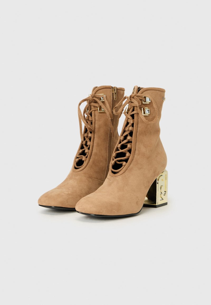 Beige Wildleder-Ankle Boots mit spitzem Zeh, Frontschnürung und einem quadratischen goldenen Akzentabsatz. Mit Reißverschlüssen an den Seiten für einfaches An- und Ausziehen.