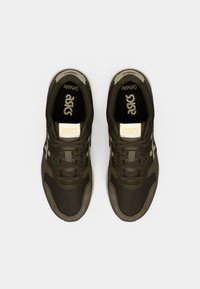 Ciemnozielone buty sportowe o teksturowanym wykończeniu. Cechy to wyściełany kołnierz, sznurówki i kontrastowe akcenty logo w kolorze białym.