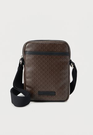 Bruine crossbodytas met een patroon, een gladde buitenkant, zwarte accenten, ritssluiting en een verstelbare riem. Voorzien van een logo aan de voorkant.