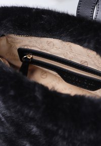 Borsa a mano in finta pelliccia nera con fodera in tessuto beige e una tasca interna con zip rifinita in pelle e zip dorata.