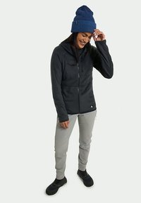 Must ülikond mustast fliisist, millel on kapuuts, heledat hallid püksid ja mustad kingad. Sinine sooniline kudumine kübar. Sile tekstuur, lihtne disain.