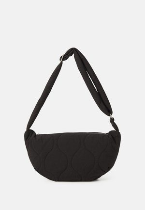 Svart quiltet veske med en buet form, med en tykk skulderreim og en sølvfarget glidelås. Jevn tekstur med bølgete mønster.