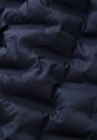 Tessuto trapuntato di colore blu navy con superficie texturizzata, caratterizzato da pieghe ondulate e finitura liscia, adatto per abbigliamento o rivestimenti.