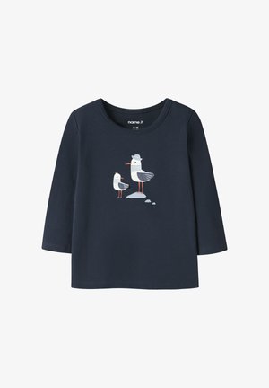 Camiseta de manga larga para niño pequeño en azul marino con dos gaviotas, una de ellas con un sombrero gris, situadas sobre pequeñas piedras en el centro.