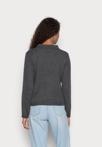 Pull en tricot gris avec col et poignets côtelés. Il présente une coupe droite, une texture douce et un design uni. Vue de dos visible.