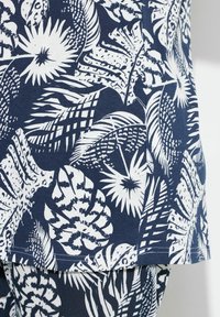 Námořnická tkanina s bílými tropickými vzory listů a květin; má hladkou texturu a uvolněný střih; švy viditelné na lemu.