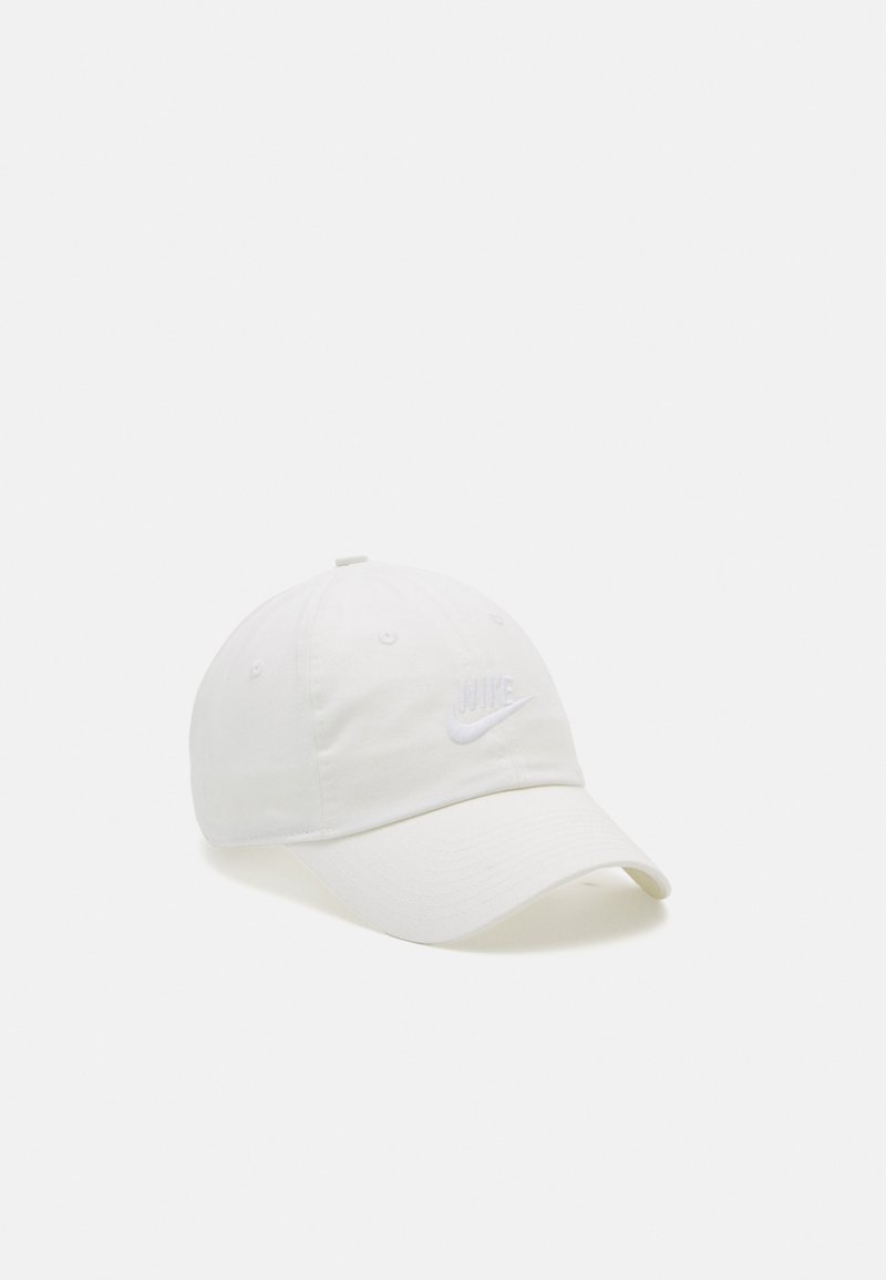 Balta medvilninė beisbolo kepuraitė su užlenktu kraštu, ant kurios priekyje yra iškaltas baltas "Nike" logotipas, o šonuose yra ventiliaciniai skylutės.