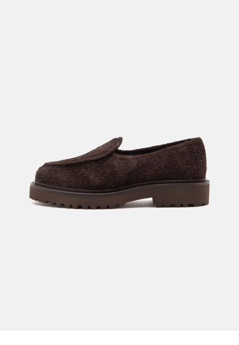 Σκούρο καφέ loafer με υφή, χοντρή σόλα και χαμηλό τακούνι, απεικονιζόμενο από το πλάι σε απλό φωτεινό φόντο.